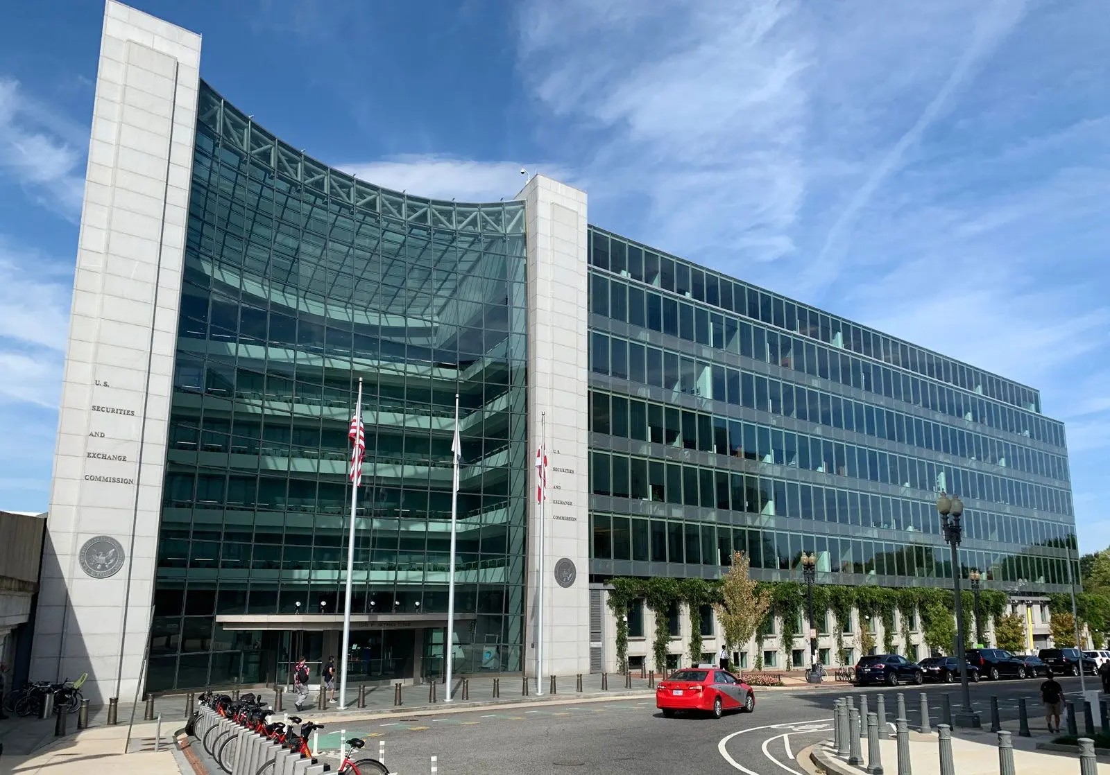 Exterior view of the U.S. Securities and Exchange Commission building with its curved glass facade and American flags