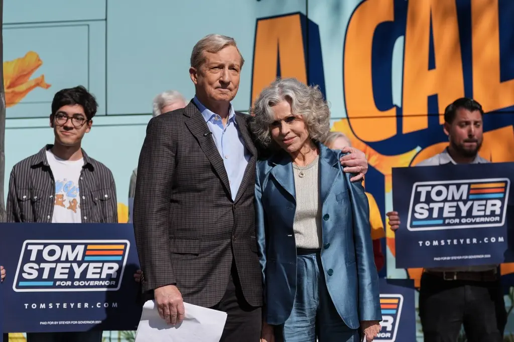 Tom Steyer standing with a woman and supporters holding Tom Steyer for Governor campaign signs.